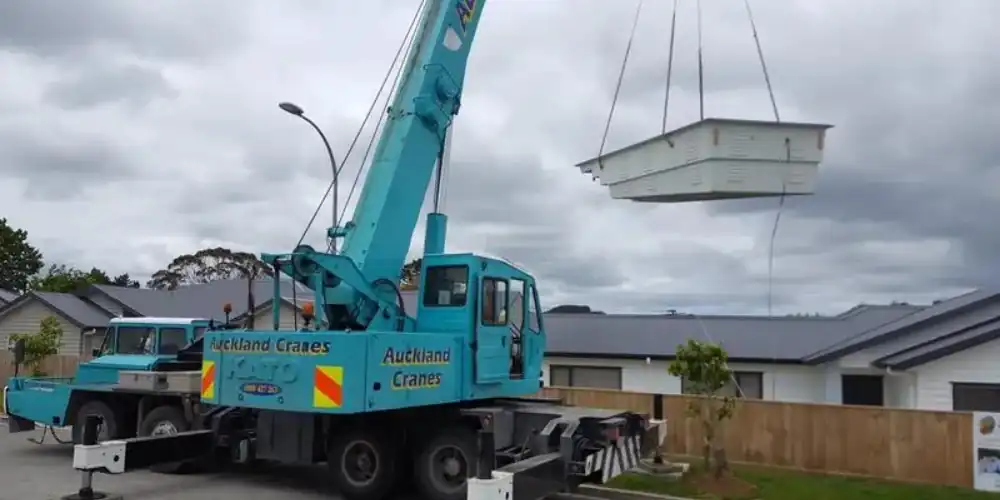 Fibreglass swimming pool being lowered by a crane into a customers backyard